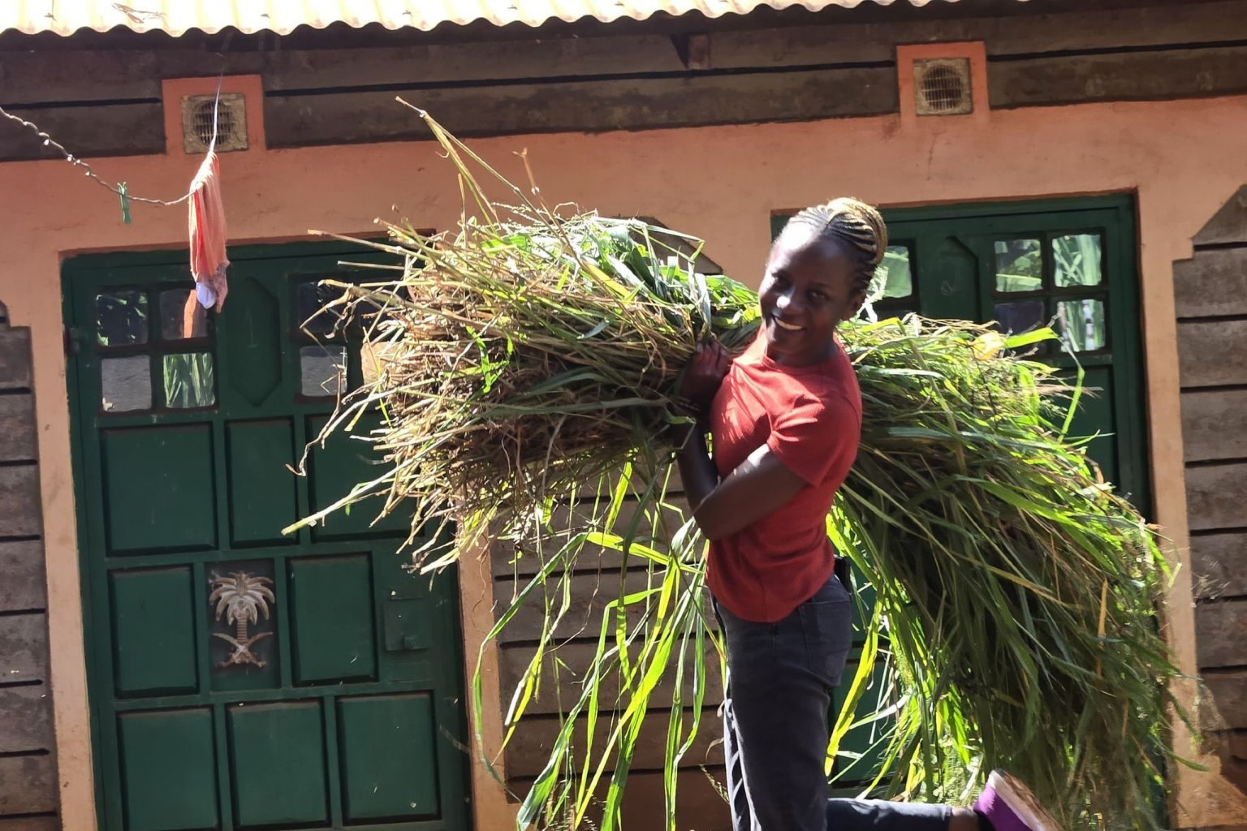 A smiling woman holding a large bundle of plants mid-stride.