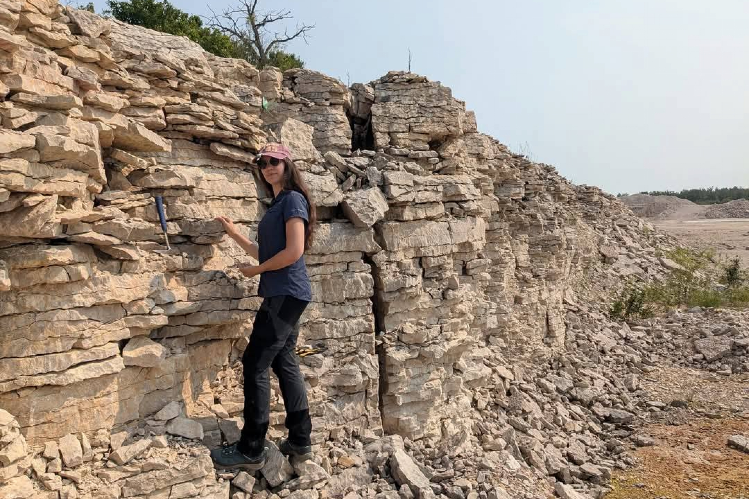 Dr. Melina Jobbins standing on rocks in a quarry near Lake Manitoba.