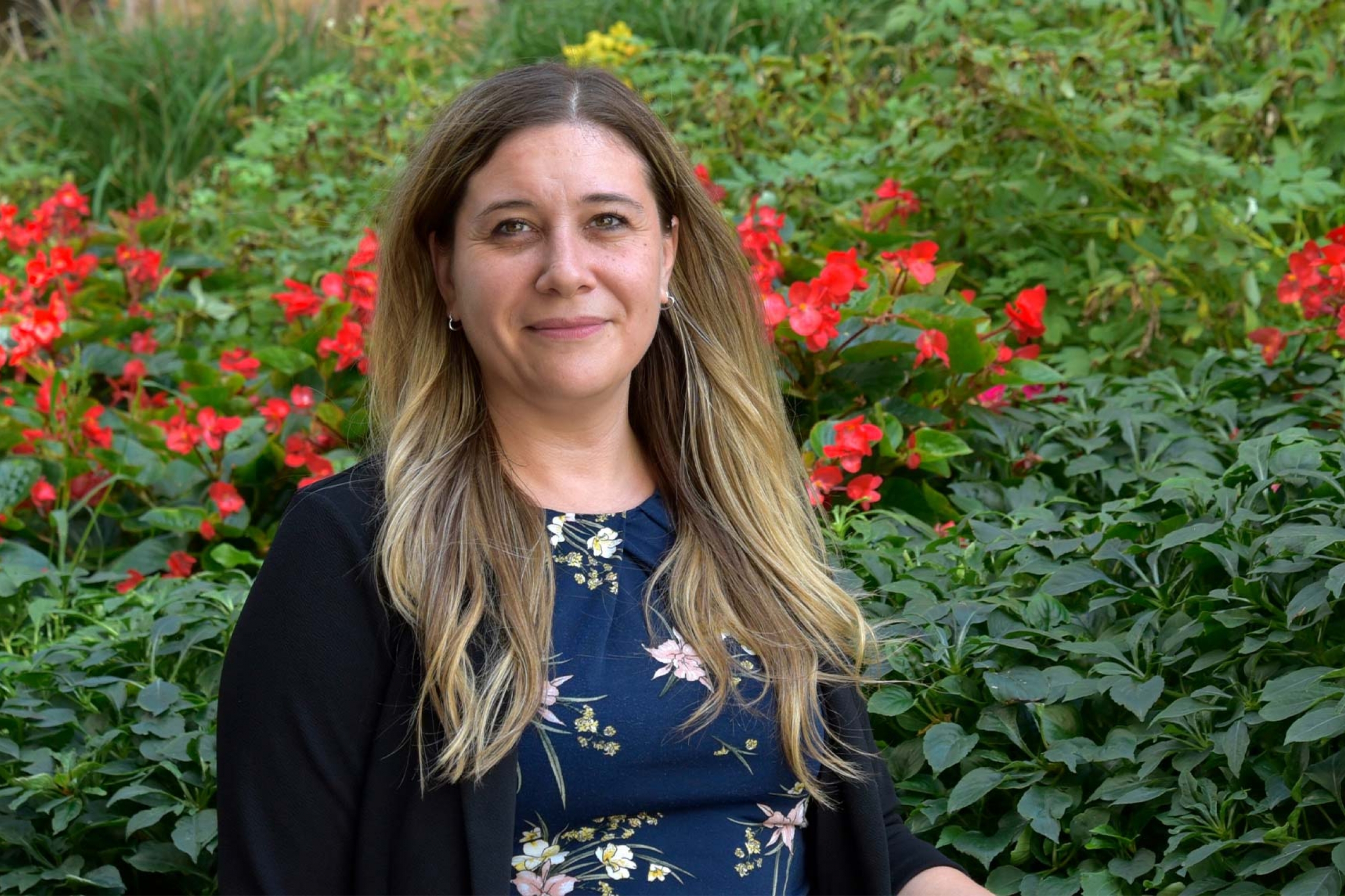 Dr. Melanie Lalonde wearing a blue patterned shirt with a black cardigan smiling at the camera.
