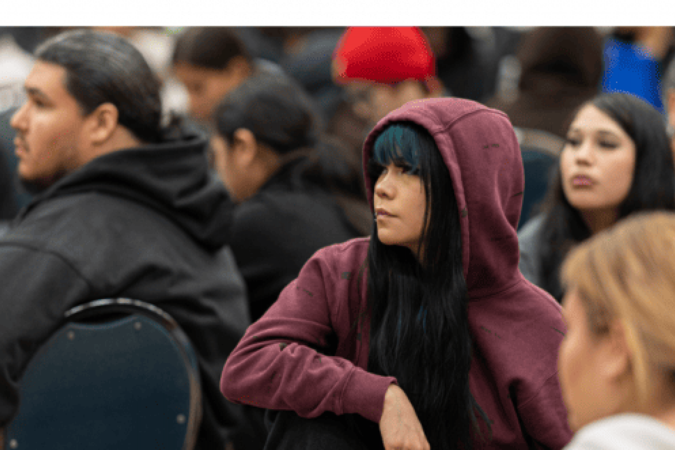 High school student looks ahead to stage while seated in crowd.