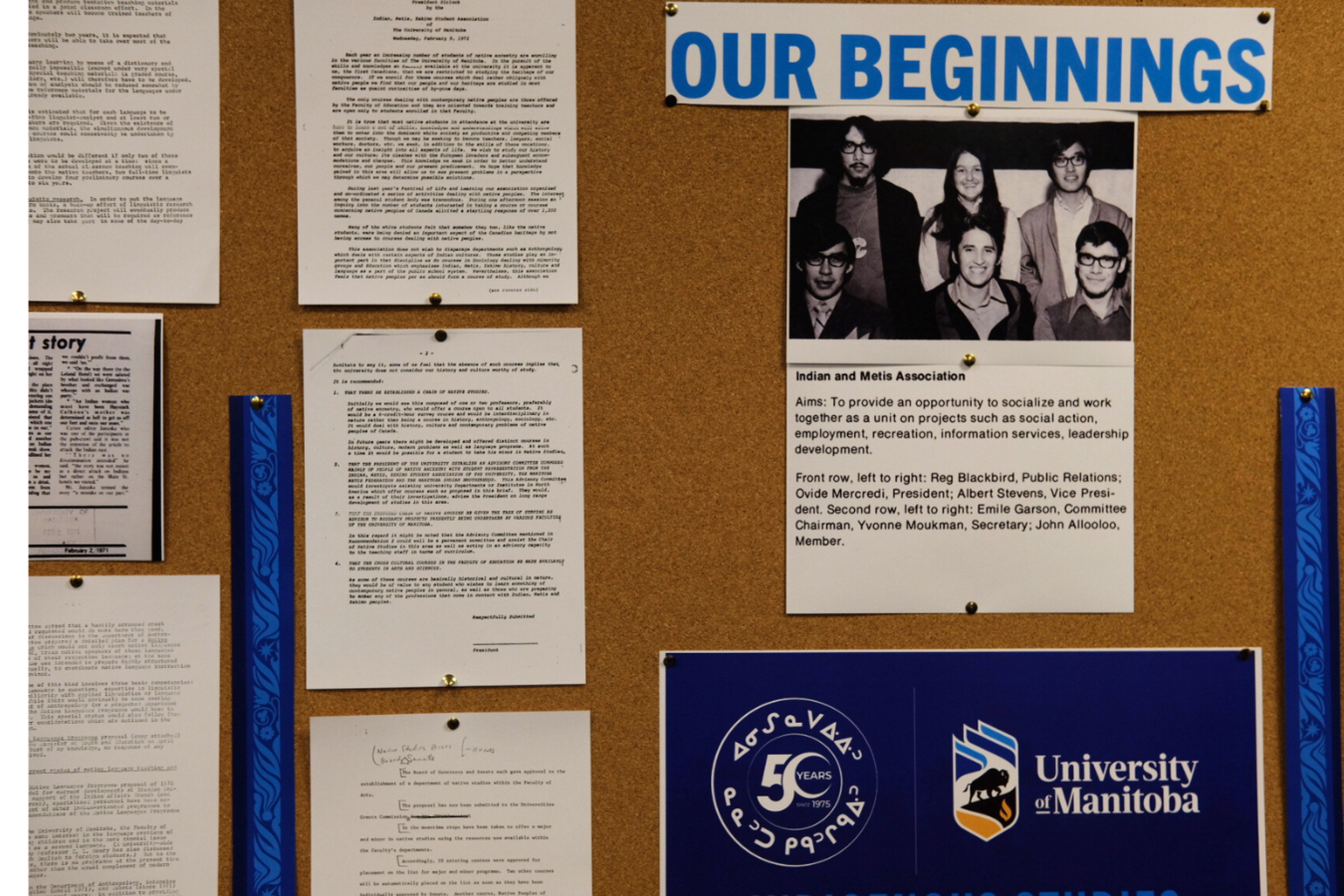 A bulletin board with historic documents and a black-and-white photo under the header “Our Beginnings.”