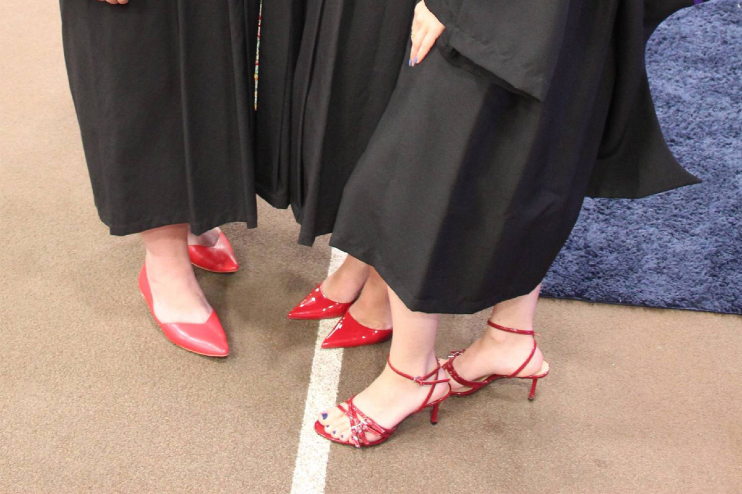 Close up of three pairs of red shoes worn by midwifery graduates.