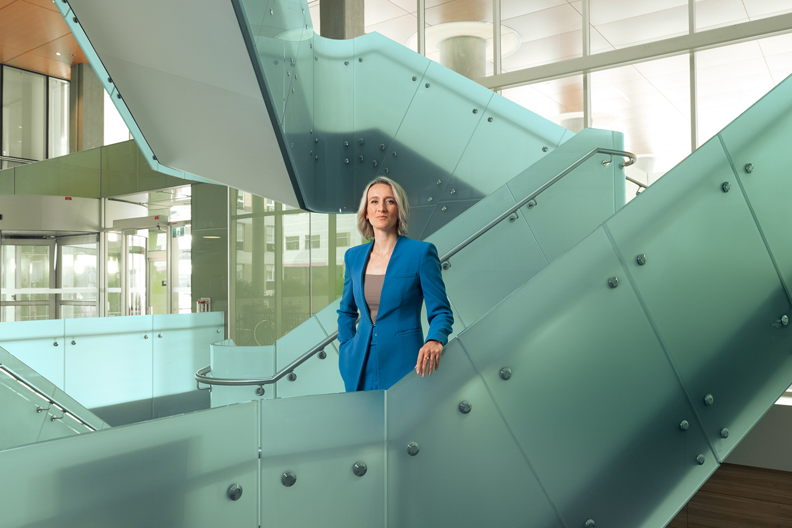 Joss Reimer faces the camera, standing on a angular stairway