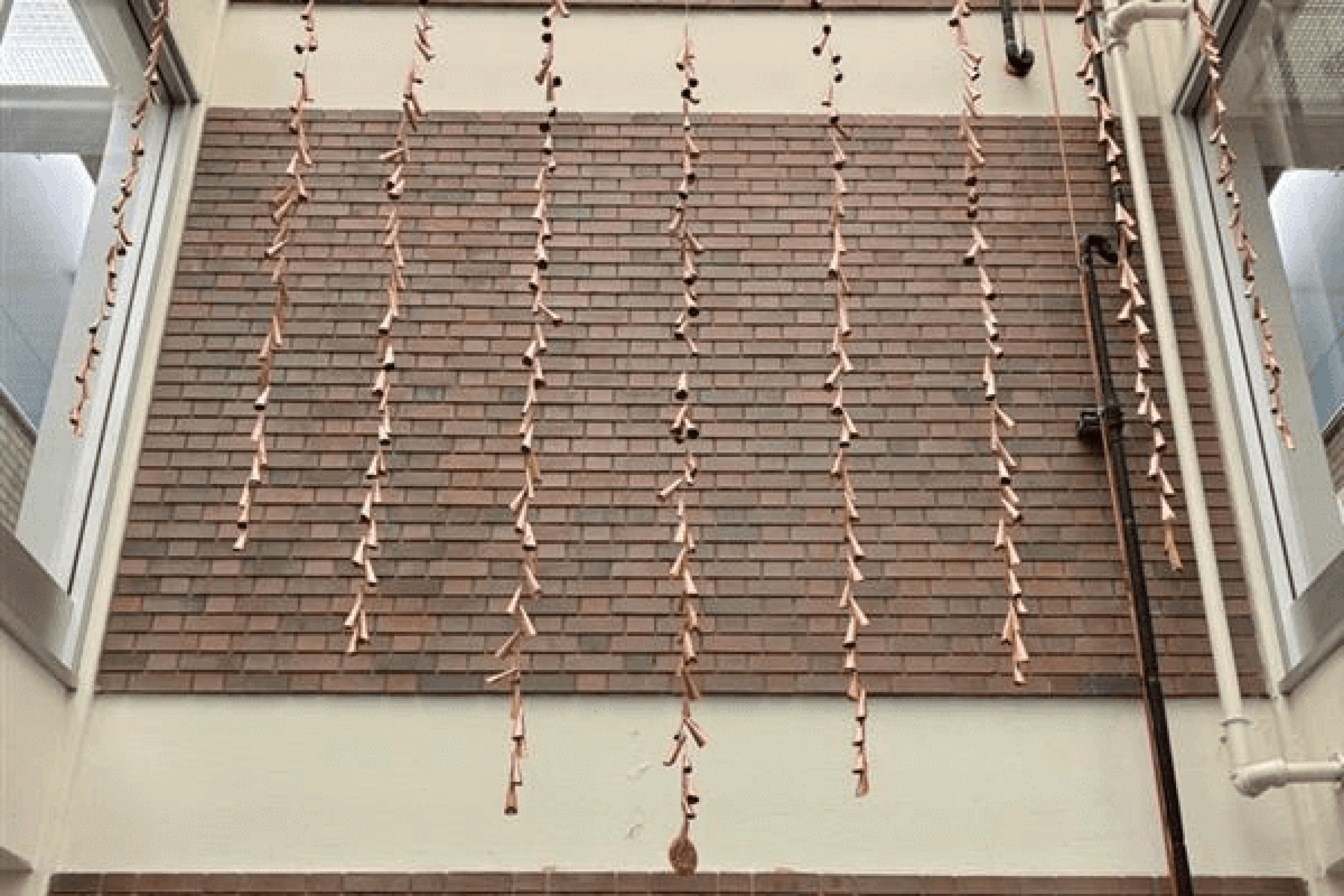 copper jingles hang from atrium with engraved cedar board below.