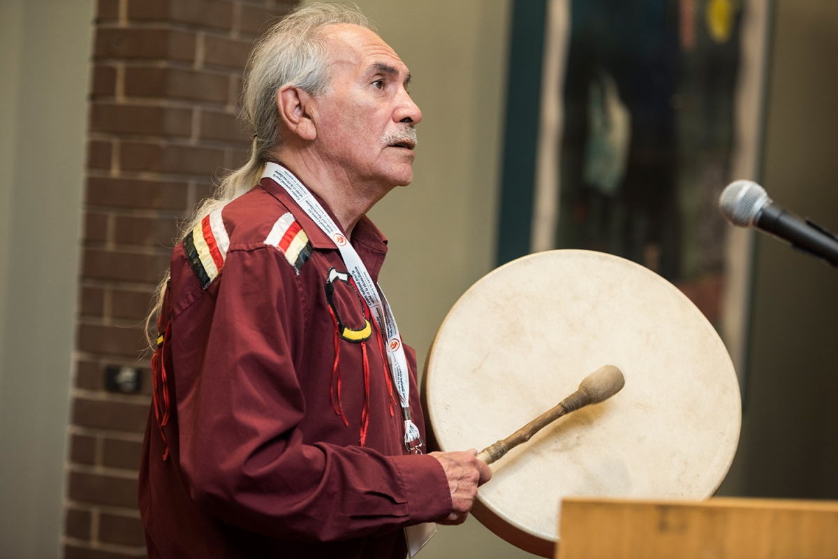 Elder Henry Skywater drums at the opening plenary.
