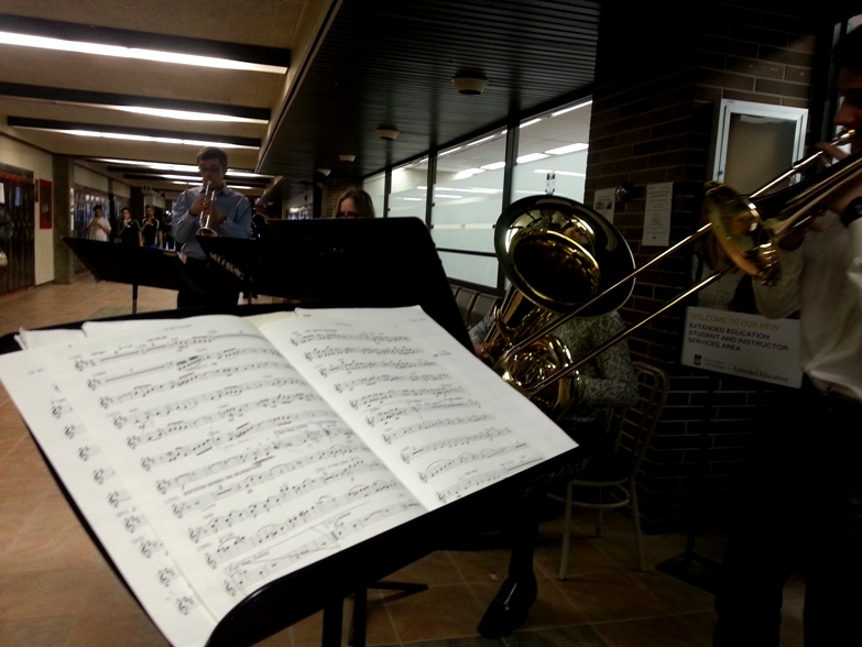 A brass ensemble plays in the hallway of extended education as students walk by