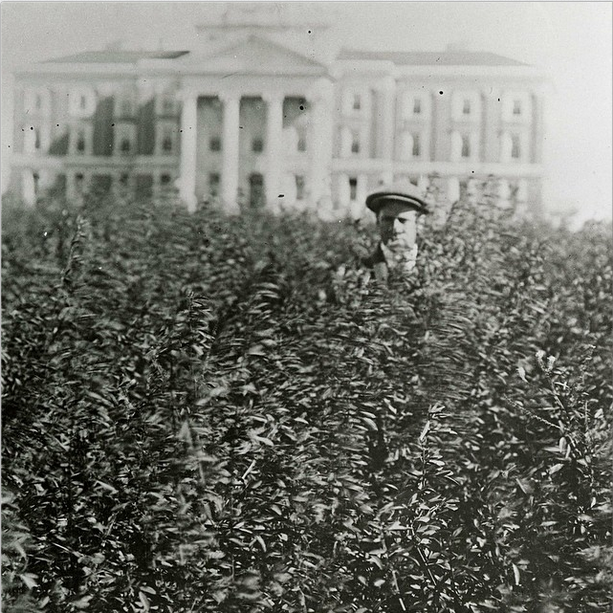 an old photo of a man in frot of teh admin building with grass up to his head