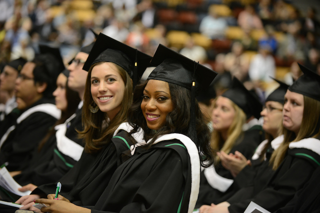 Two female students look at the camera with excitement and hope at Fall Convocation 2014