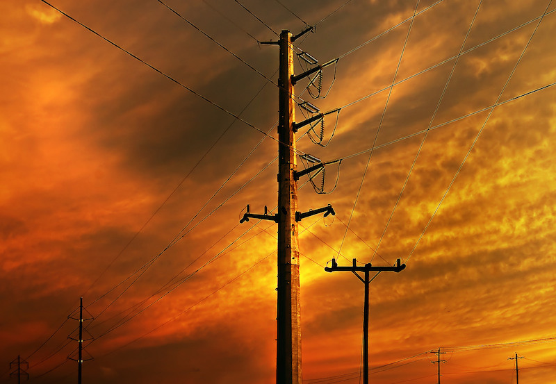 power lines against the orange sky of a setting sun