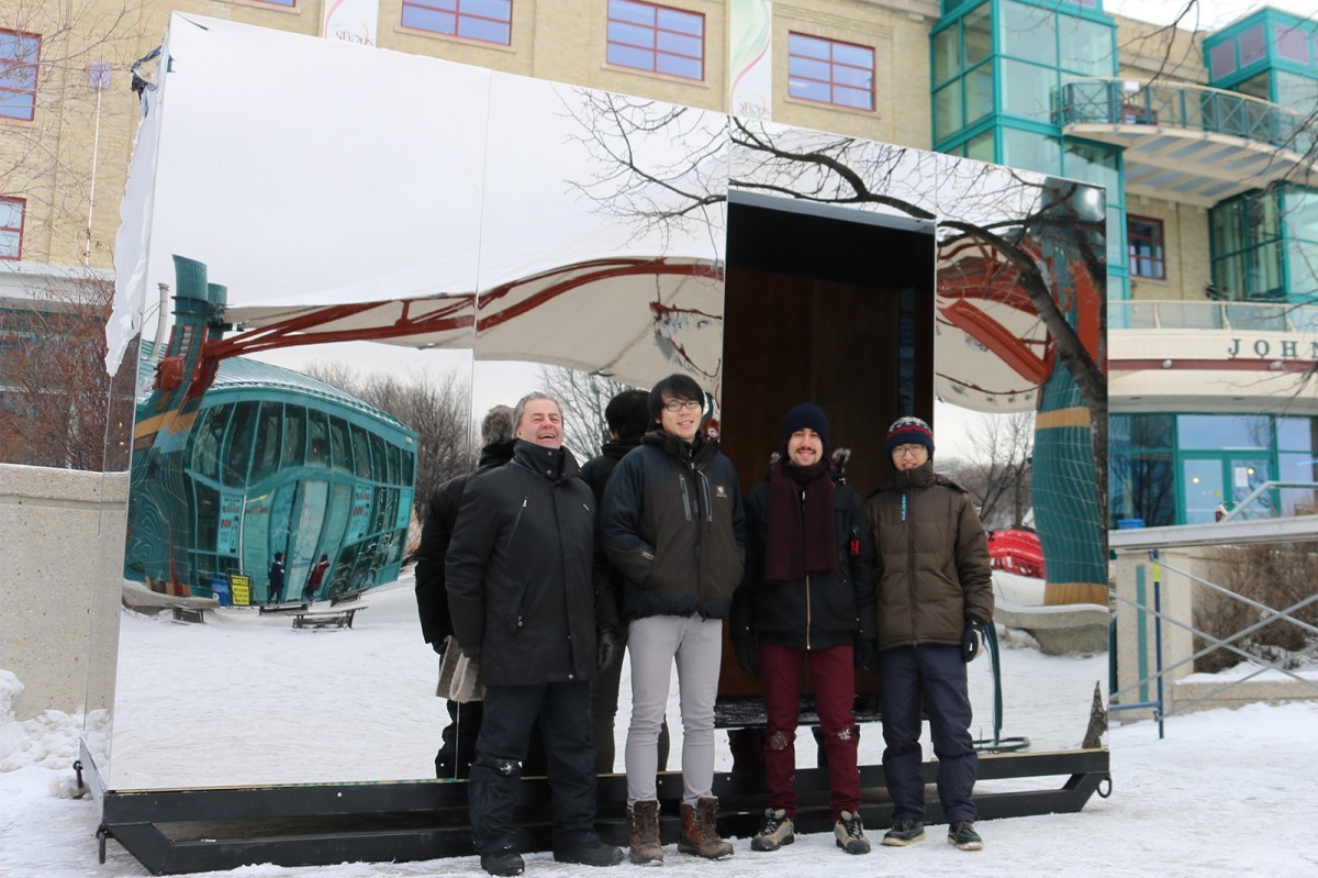 Students Yin Zheng, Wei Zou, and Rafael Vieira Leal with instructor Phillipe Perron stand in front of their warming hut entry, "Mirror Cloaking"