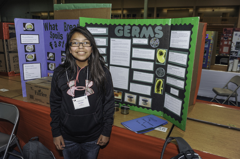 A student in front of her project, 'GERMS"
