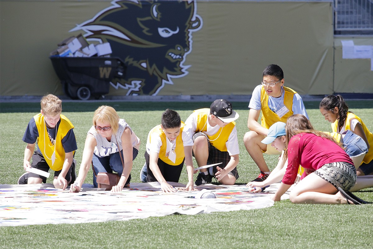 Students from the Pembina Trails School Division Human Rights Project laying out the final tiles in their mosaic at Investors Group Field