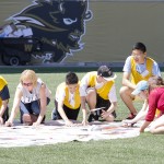 Students from the Pembina Trails School Division Human Rights Project laying out the final tiles in their mosaic at Investors Group Field