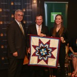 David Barnard, Frank McKenna and student Nicole Courrier with the unity blanket presented to TD Bank Group.