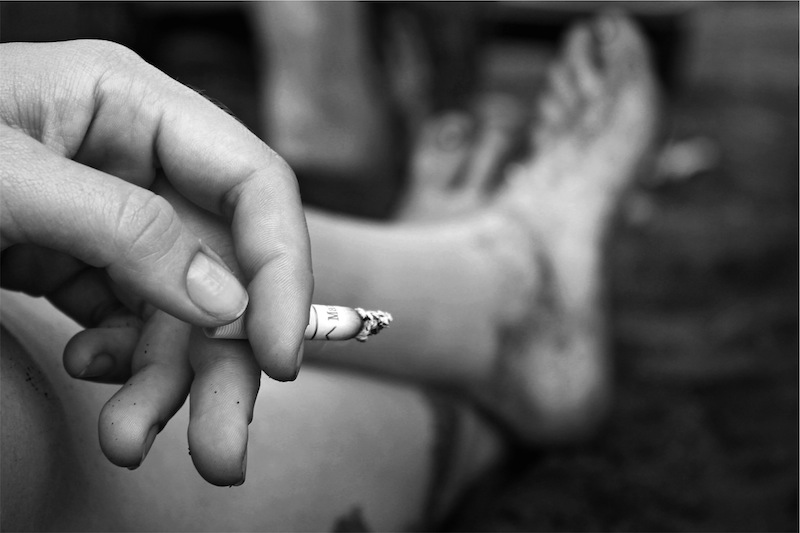 black and white image showing someone smoking a cigarette