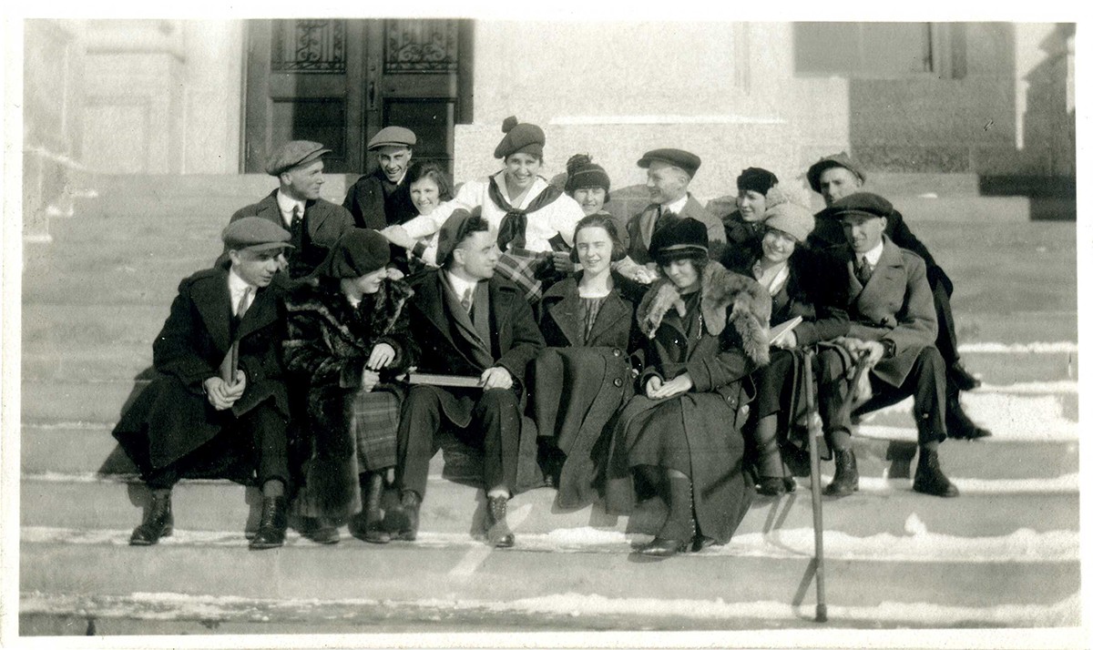Group of men and women sitting on steps. Dated 1915.