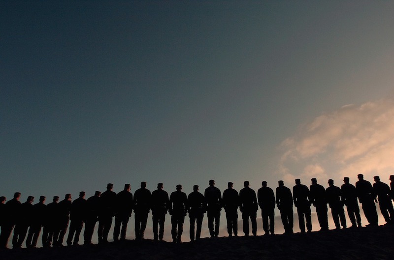 Silhouettes of soldiers standing on a ridge at sunset