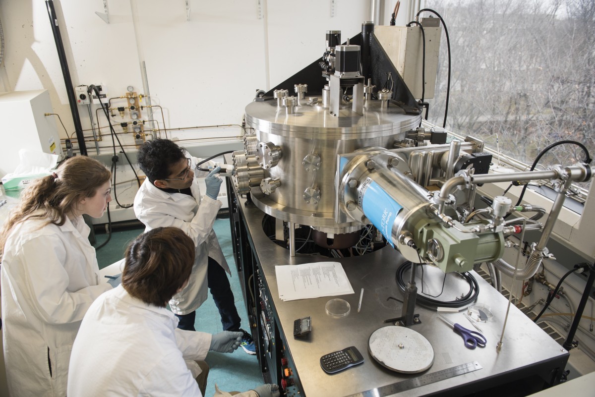 Counter-clockwise: Graduate students Sampath Liyanage, Valerie Beynon, and Byoungyoul Park operating the sputter system cluster tool used for material coating