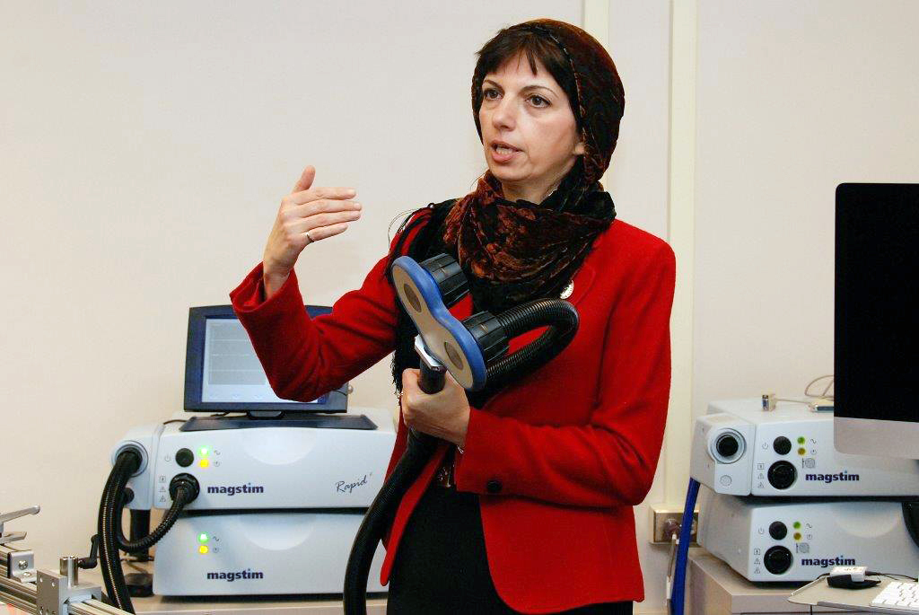 Zahra Moussavi holding a device capable of applying repetitive transcranial magnetic stimulation, which her new study will investigate as a therapy for Alzheimer’s patients.
