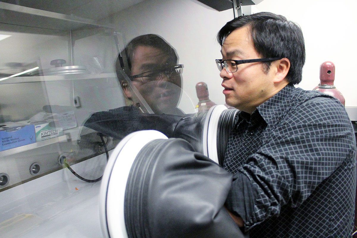 Feiyue Wang uses a glove box in his lab, allowing him to work with samples sensitive to oxygen. // Photo by Kaitlin Vitt