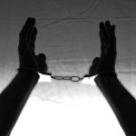 a silouhette of hands raised up in handcuffs