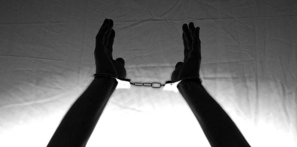 a silouhette of hands raised up in handcuffs