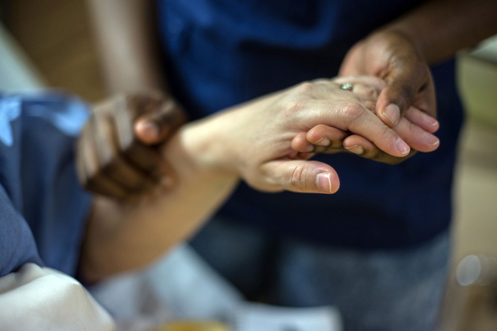 Hands being held in bedside health care.