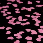 pink paper hearts cut out and laying on black cloth