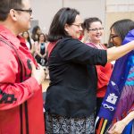 Frank Deer, Acting Executive Lead, Indigenous Achievement, and Christine Cyr, Director of the Indigenous Student Centre, present recent graduate Kristin Flattery [BFA (Hons)] with a purple scarf at the 28th Annual Graduation Pow Wow.