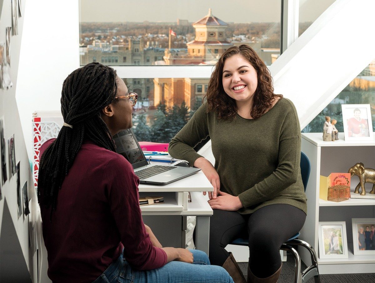 Morgan Hanson-Oliveira sits with another student in a student residence overlooking the Administration building.