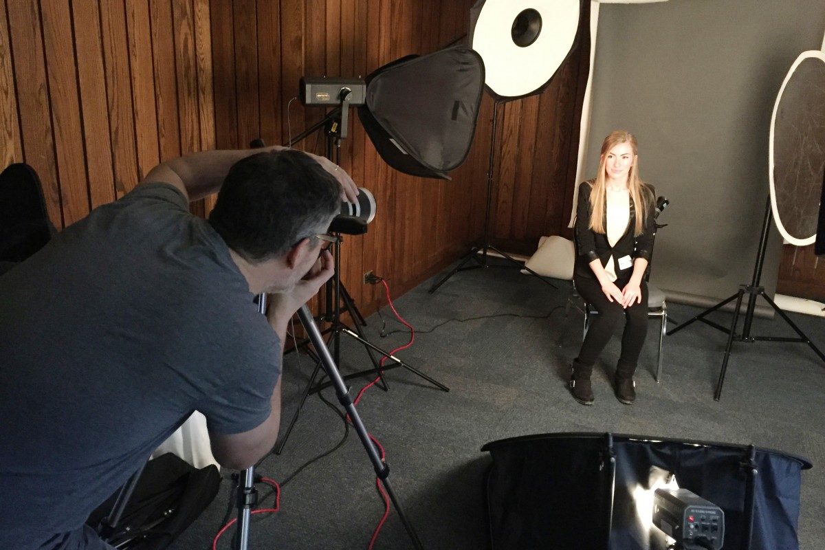A student poses in front of a photographer for a free headshot at the Career Fair