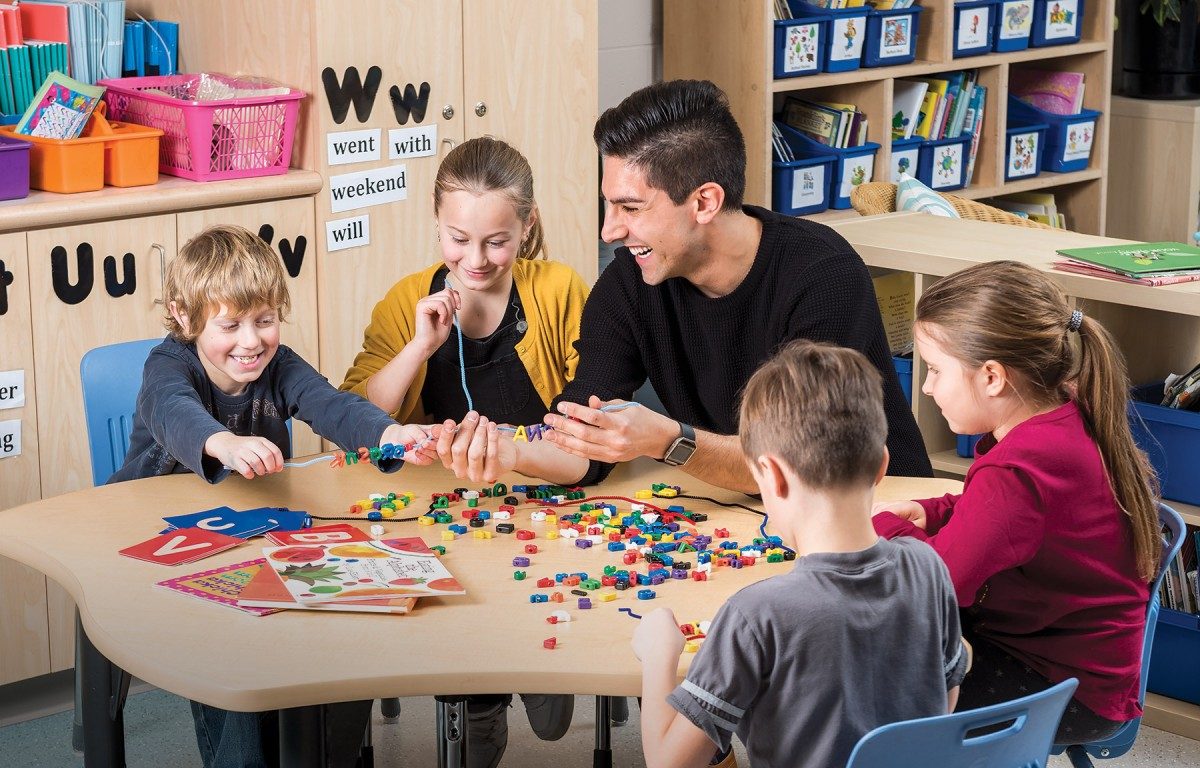 Gaston Lopez Ficher sits with young students at a table