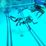 An underwater football player is trying to complete a pass to another player.