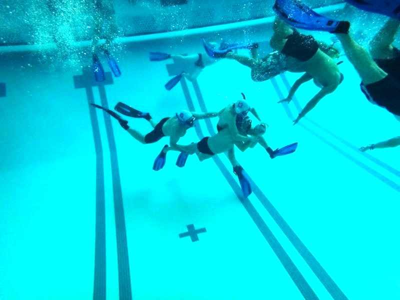 An underwater football player is trying to complete a pass to another player.