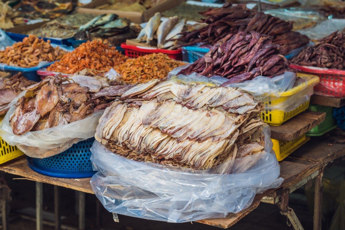 A selection of dried fish and seafood displayed for sale in a Southeast Asian market.