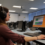 Student using computer and headphones, practicing in the Language Centre