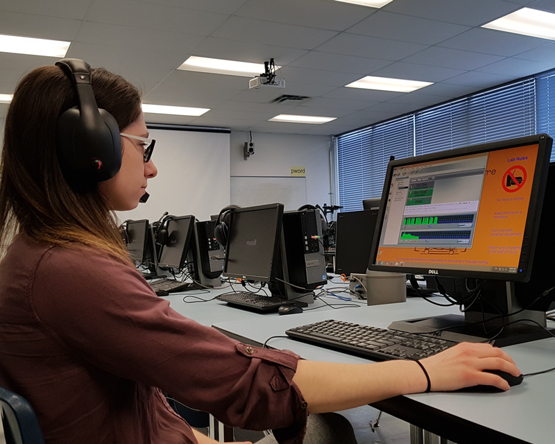 Student using computer and headphones, practicing in the Language Centre