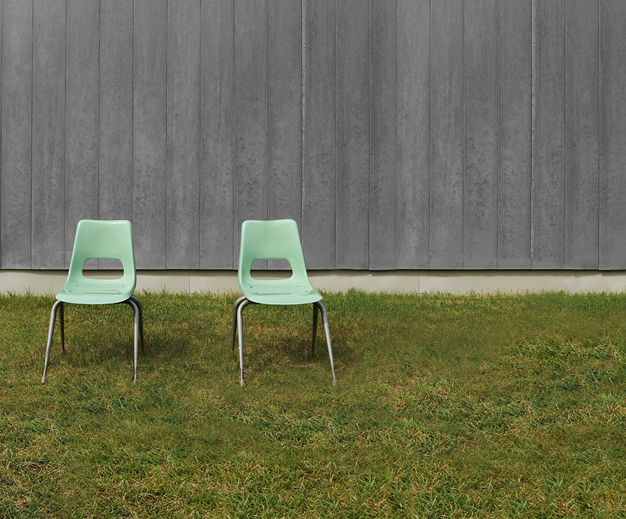 Two empty chairs in front of a wall, outdoors.