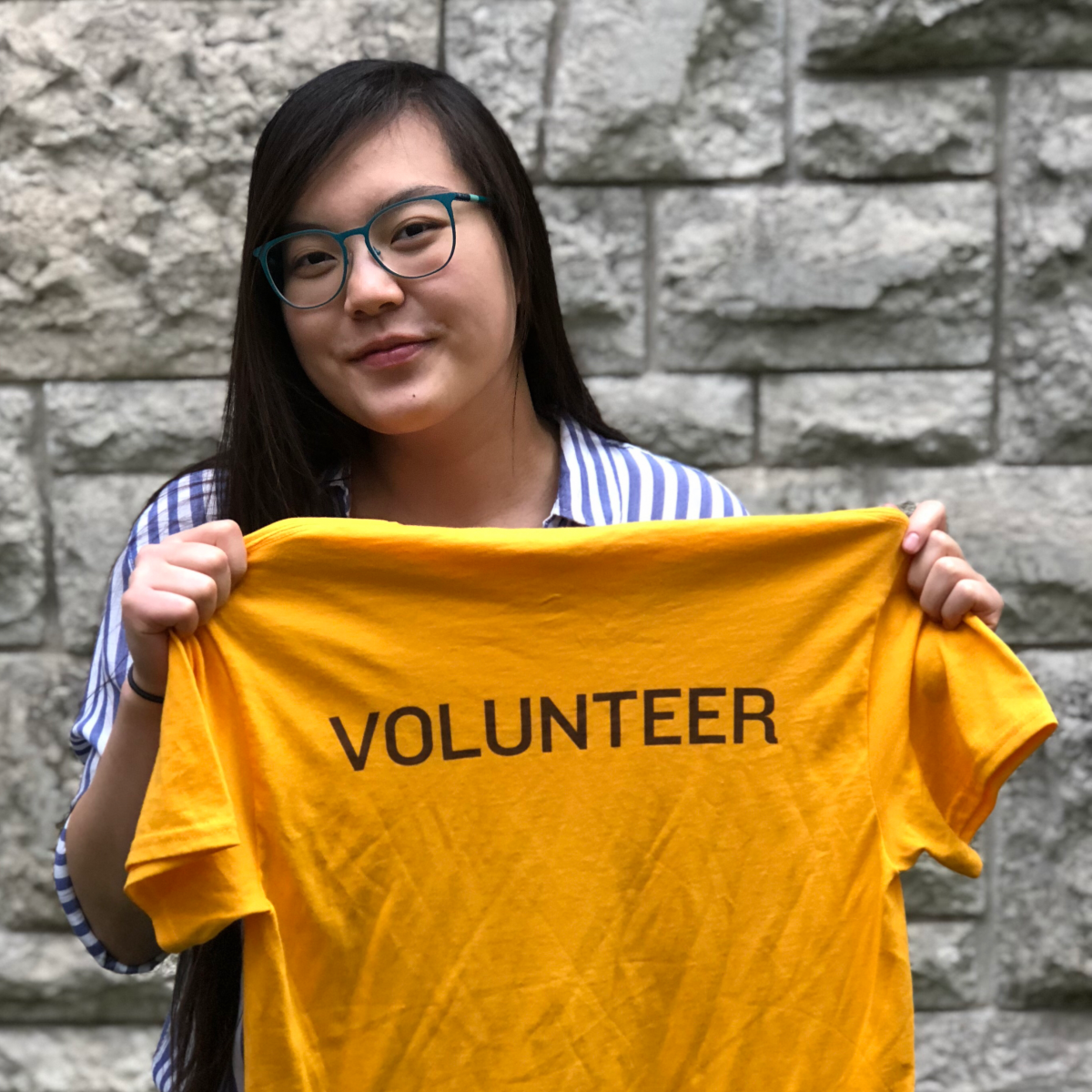 Nina Lam holding gold volunteer shirt