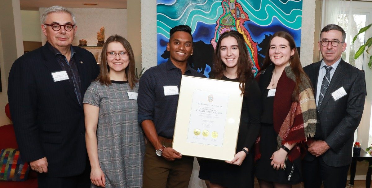 Students stand with the President in his house alongside the Dean