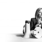 Anne Mahon sits with a trio of megaphones, hands clasped.
