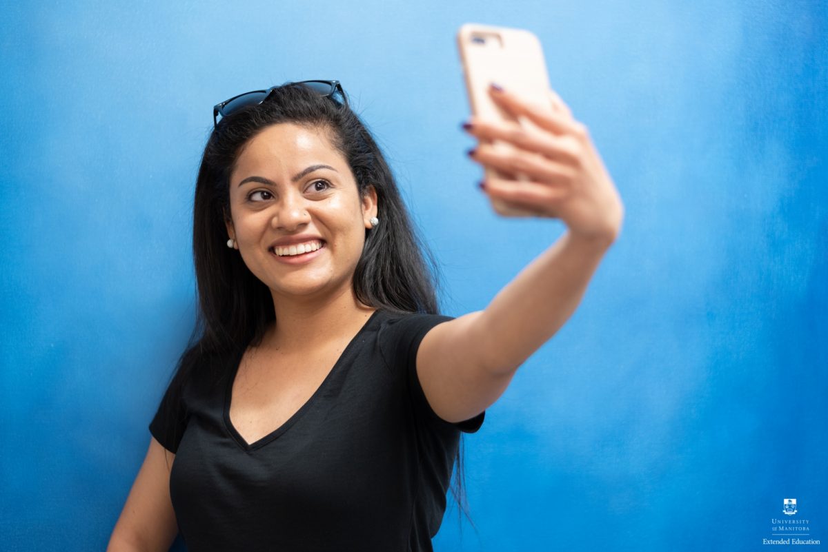 Student Seebia Bharadwaj takes a selfie by the art in Extended Education.