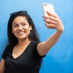 Student Seebia Bharadwaj takes a selfie by the art in Extended Education.