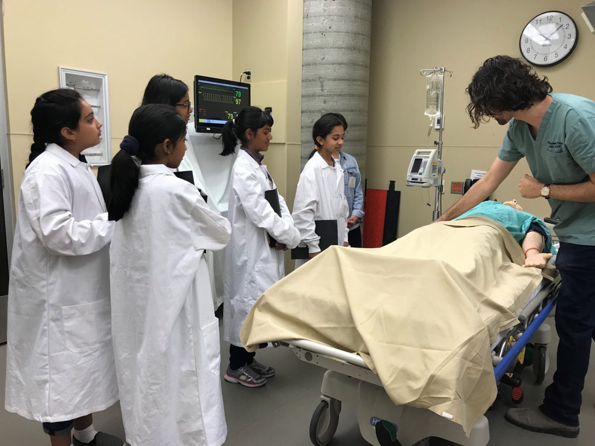 Students and a doctor do an exercise with a manikin