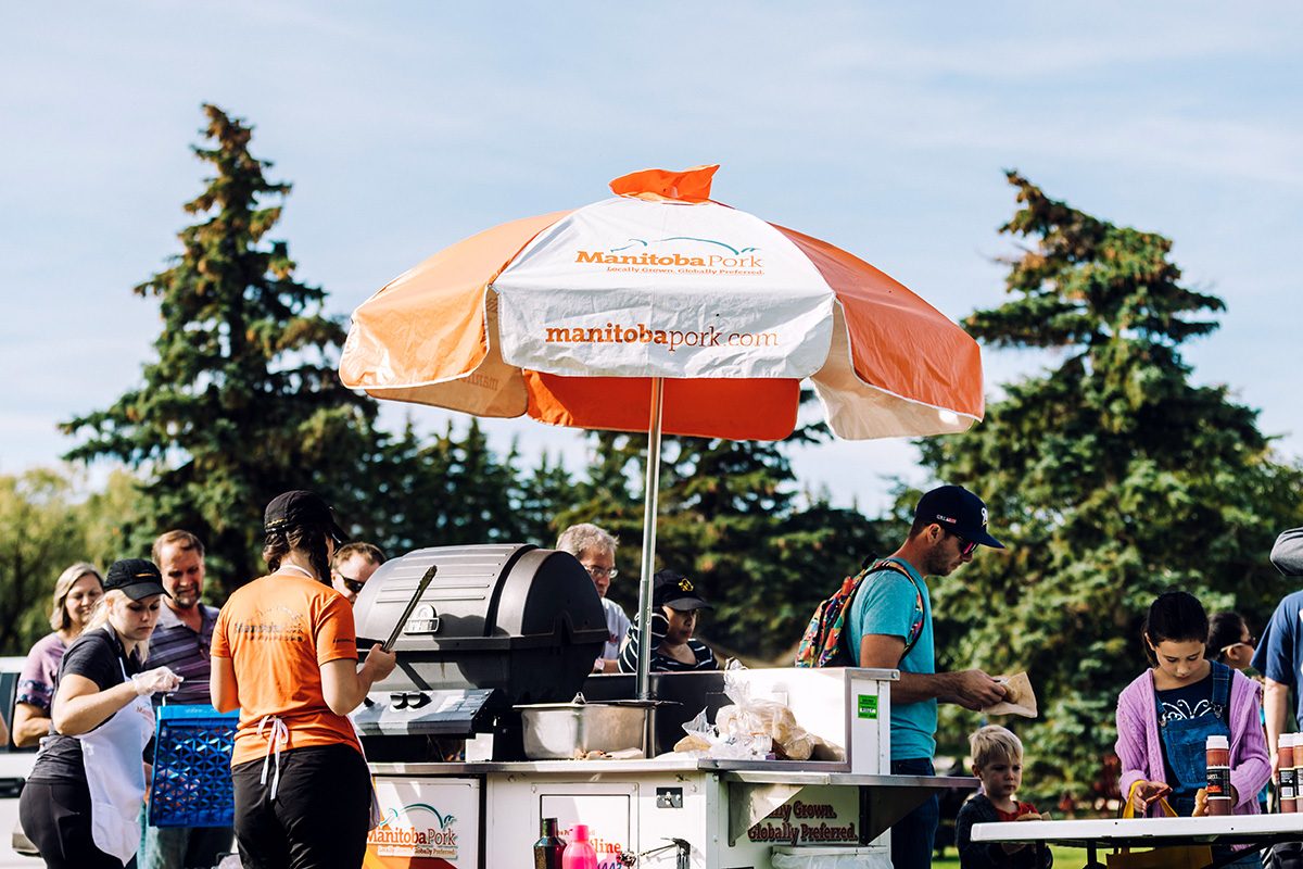 Representatives from Manitoba Pork serve pork on a bun to participants at Open Farm Day 2019 at the Bruce D. Campbell Farm and Food Discovery Centre.