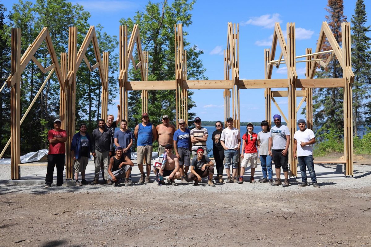 Engineering and Architecture students and faculty pose outside of a structure in progress.