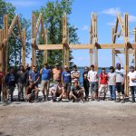 Engineering and Architecture students and faculty pose outside of a structure in progress.