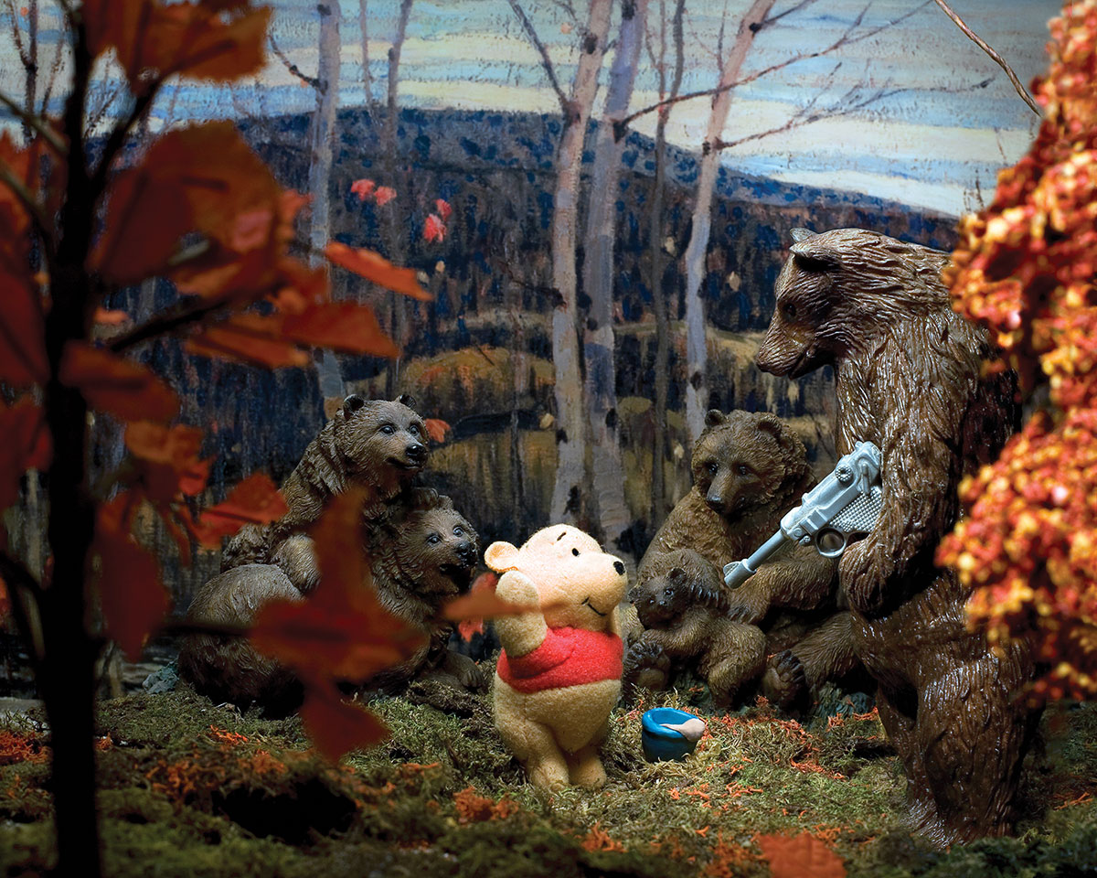 A photo of a sculpture of a group of bears surrounding Winnie the Pooh. One of the bears is holding a gun and Pooh has his hands up in the air.
