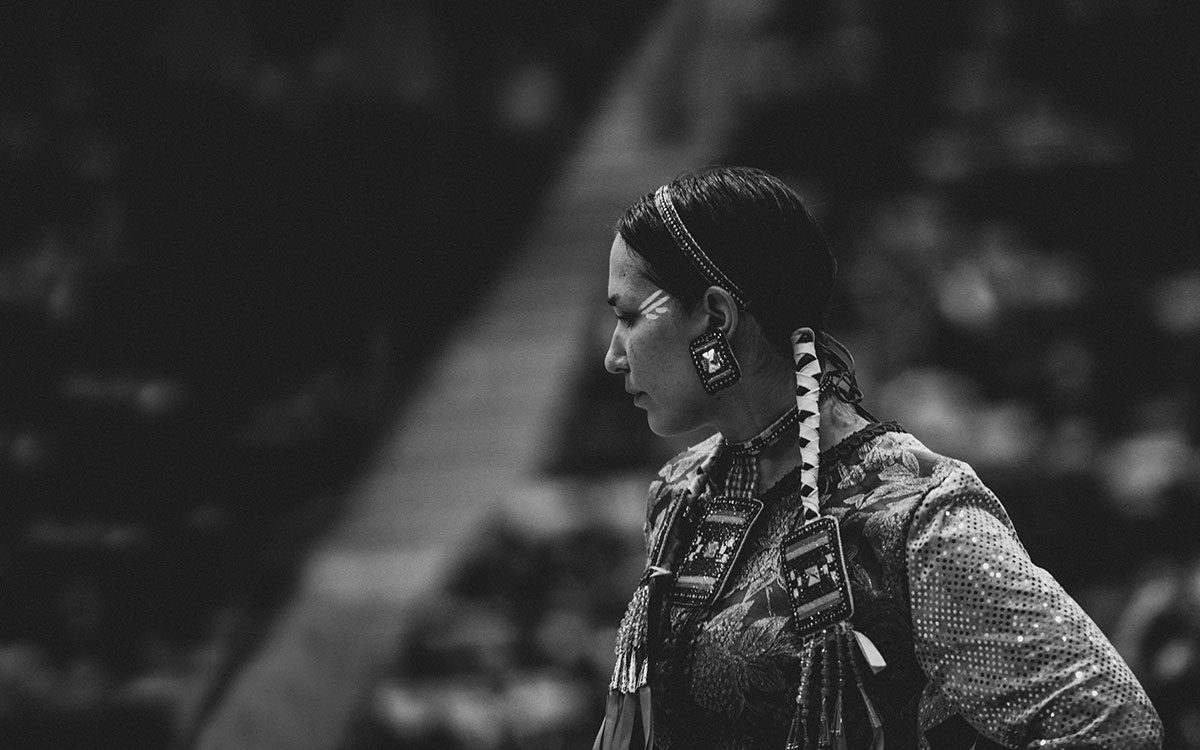 A woman dances in a black and white photo of a pow wow.