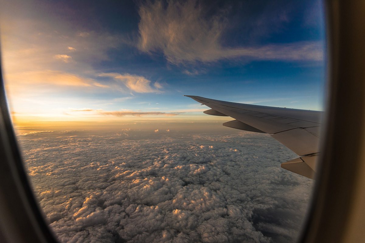 Looking out over clouds and the wing of an airplane in flight. // Image from Pixabay